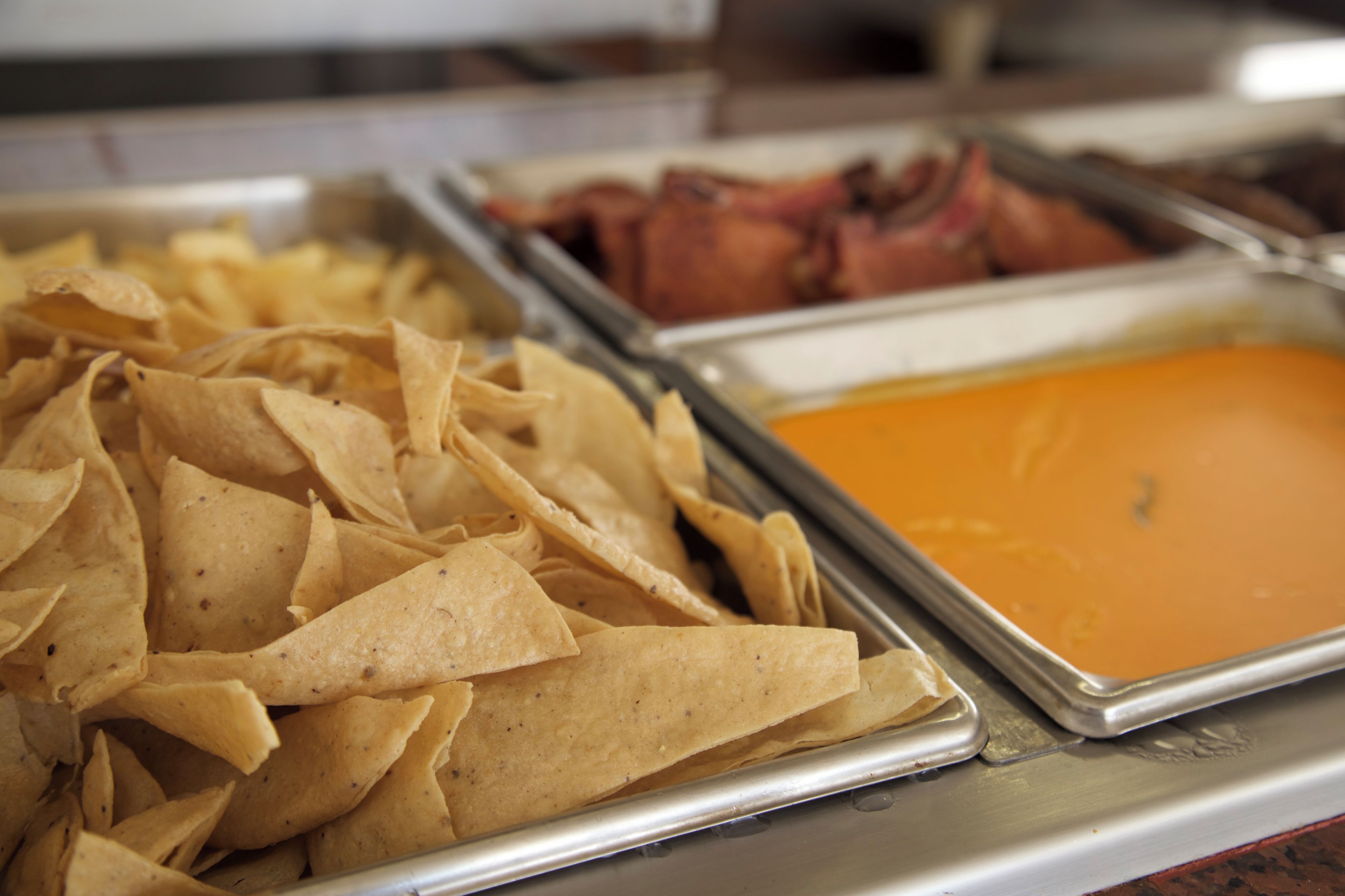 A buffet with various food items including chips and a container of orange dip.