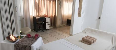 A bedroom with a bed, a desk, and a chair. There is a door leading to another room.
