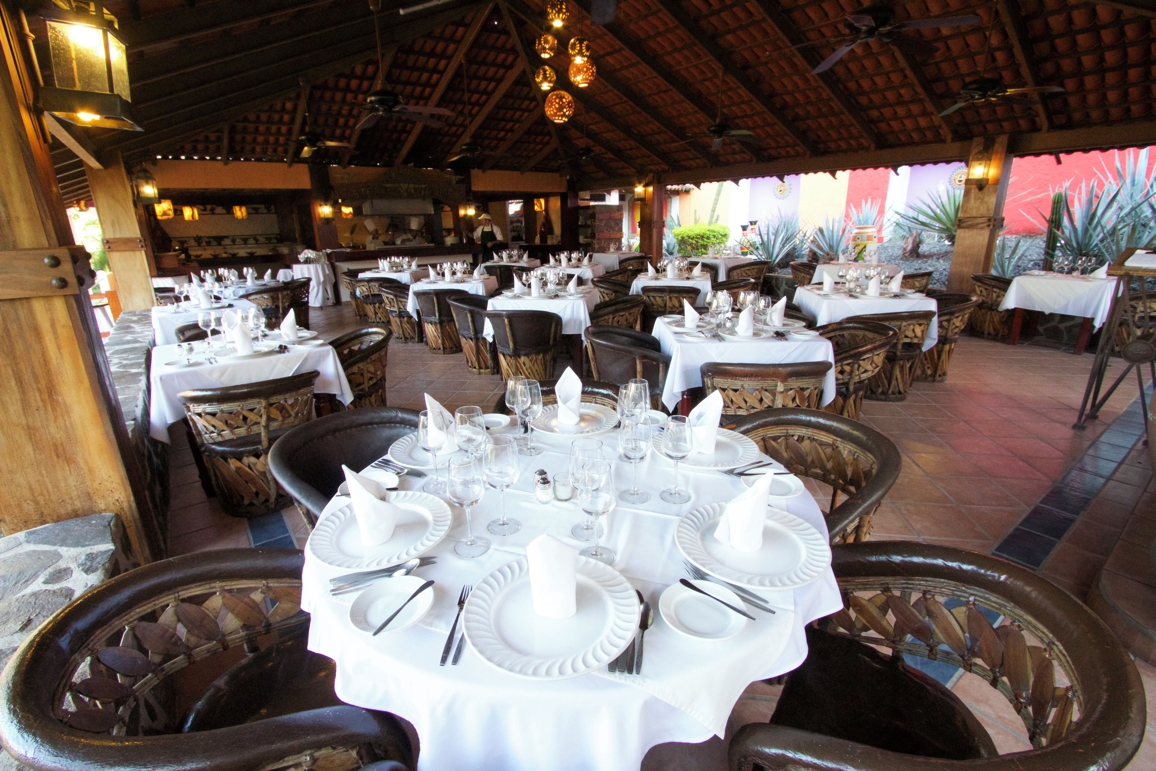 A restaurant with round tables set for dining, featuring white tablecloths and chairs.