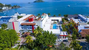 Un pueblo costero con edificios, una piscina y barcos en el agua.
