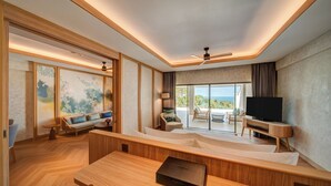 A modern living room with a wooden floor, a sofa set, a television, and a dining table. - Mövenpick Resort & Spa Bintan Lagoon (Bintan)