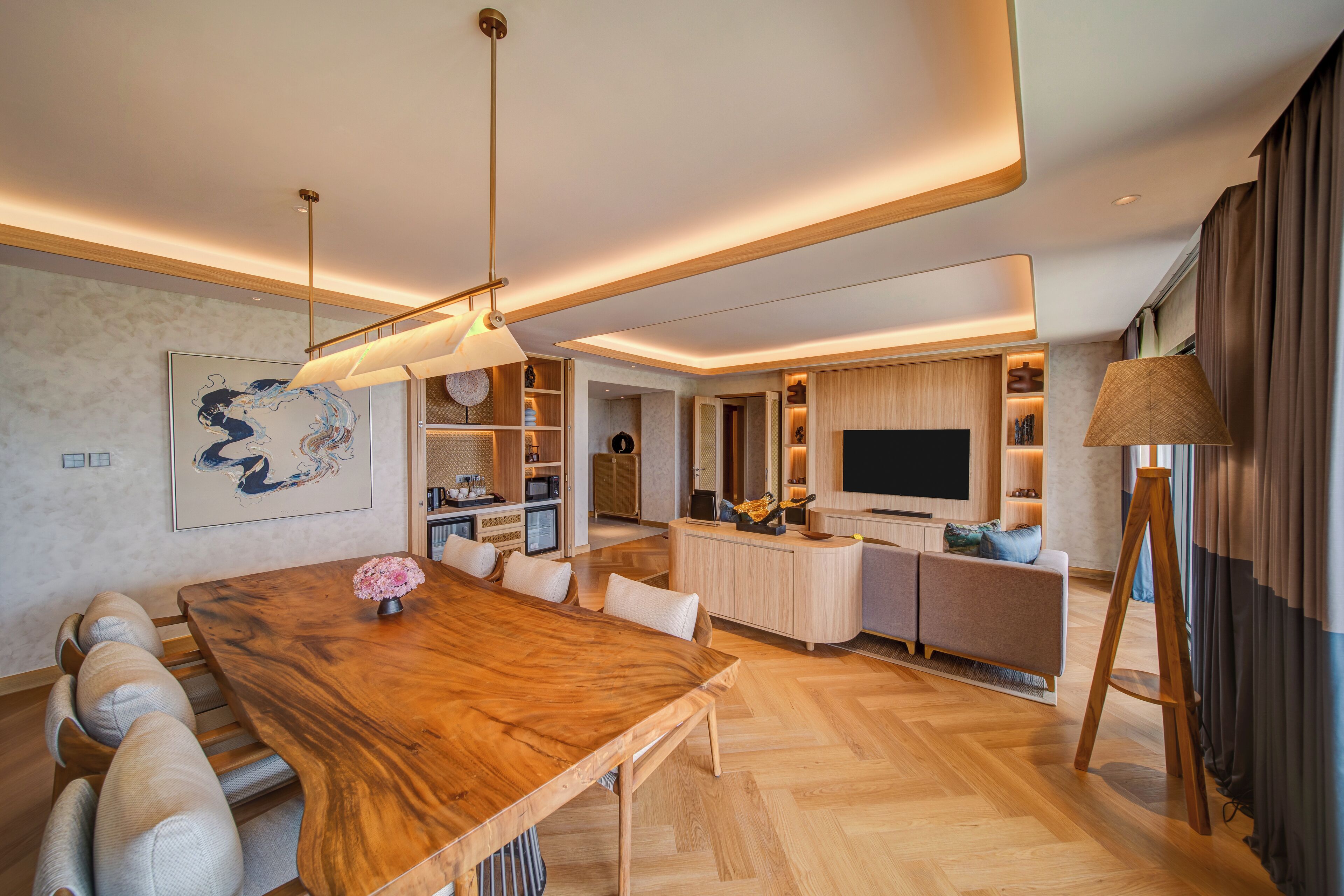 A modern living room with a wooden dining table, sofa, and TV.