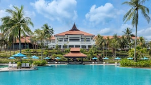 Un resort con una piscina grande, palmeras y un edificio de techo rojo.