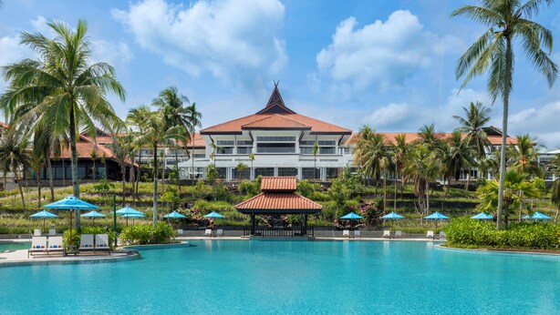 A resort with a large pool, palm trees, and a building with a red roof. - Mövenpick Resort & Spa Bintan Lagoon (Bintan)