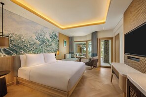 A hotel room with a large bed, a desk, a chair, a TV, and a mural on the wall. - Mövenpick Resort & Spa Bintan Lagoon (Bintan)