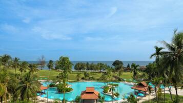 A resort with multiple swimming pools, palm trees, and a view of the ocean.