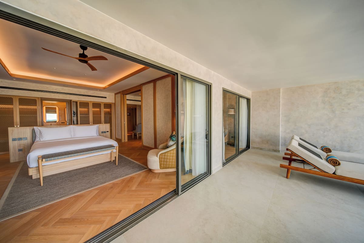 A modern bedroom with a bed, a bench, and a ceiling fan.