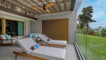Un balcon avec des fauteuils de jardin, un ventilateur de plafond et une vue sur l’extérieur.