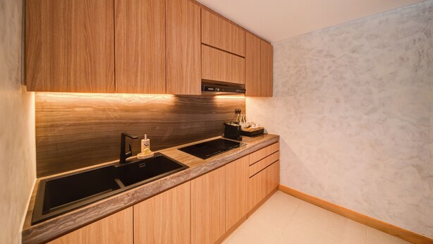 Una cocina moderna con armarios de madera, un lavamanos negro y un horno empotrado.