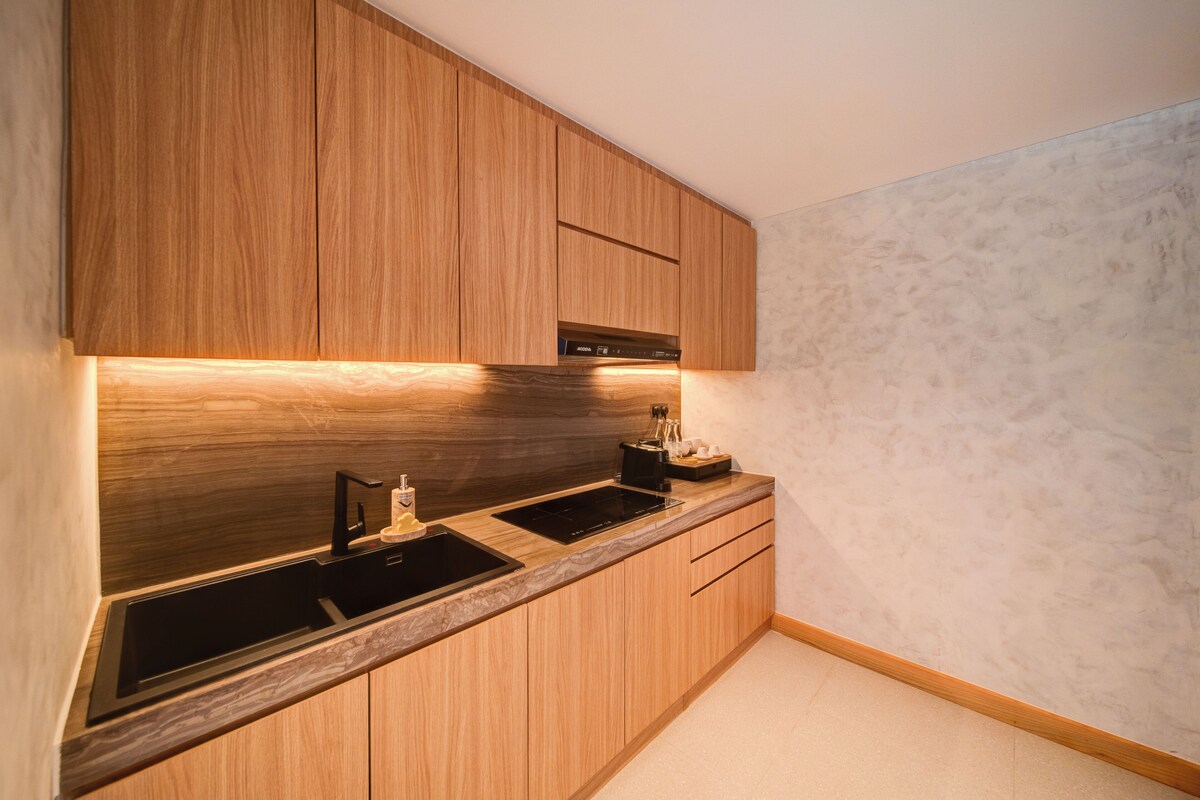 A modern kitchen with wooden cabinets, a black sink, and a built-in oven.