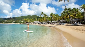 Une plage avec une eau cristalline, des palmiers et des parasols.