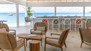 Un espace extérieur abrité, avec des chaises et des tables en osier, un bar et une vue sur l’océan.