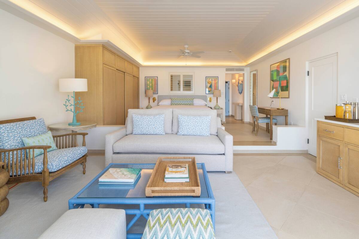 A spacious living area with a sofa, coffee table, and a dining area with chairs.