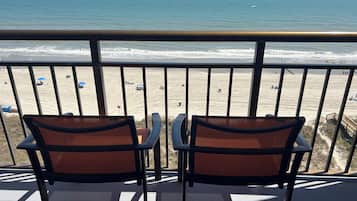 A balcony with two chairs facing a beach.