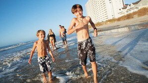 Eine Strandansicht mit Menschen, die im flachen Wasser entlanggehen.
