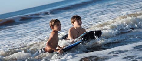 Two children on a surfboard in the ocean.