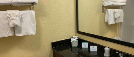 Baño con lavamanos, inodoro y espejo que refleja toallas.