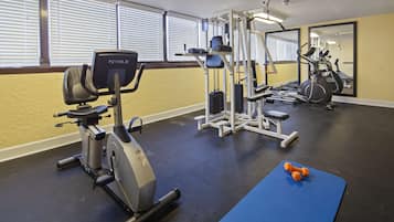 A gym with exercise equipment, a blue mat, and dumbbells.