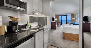 A hotel room with a kitchenette, a bed, a TV, and a view of the ocean. - Best Western Ocean Sands Beach Resort (North Myrtle Beach)