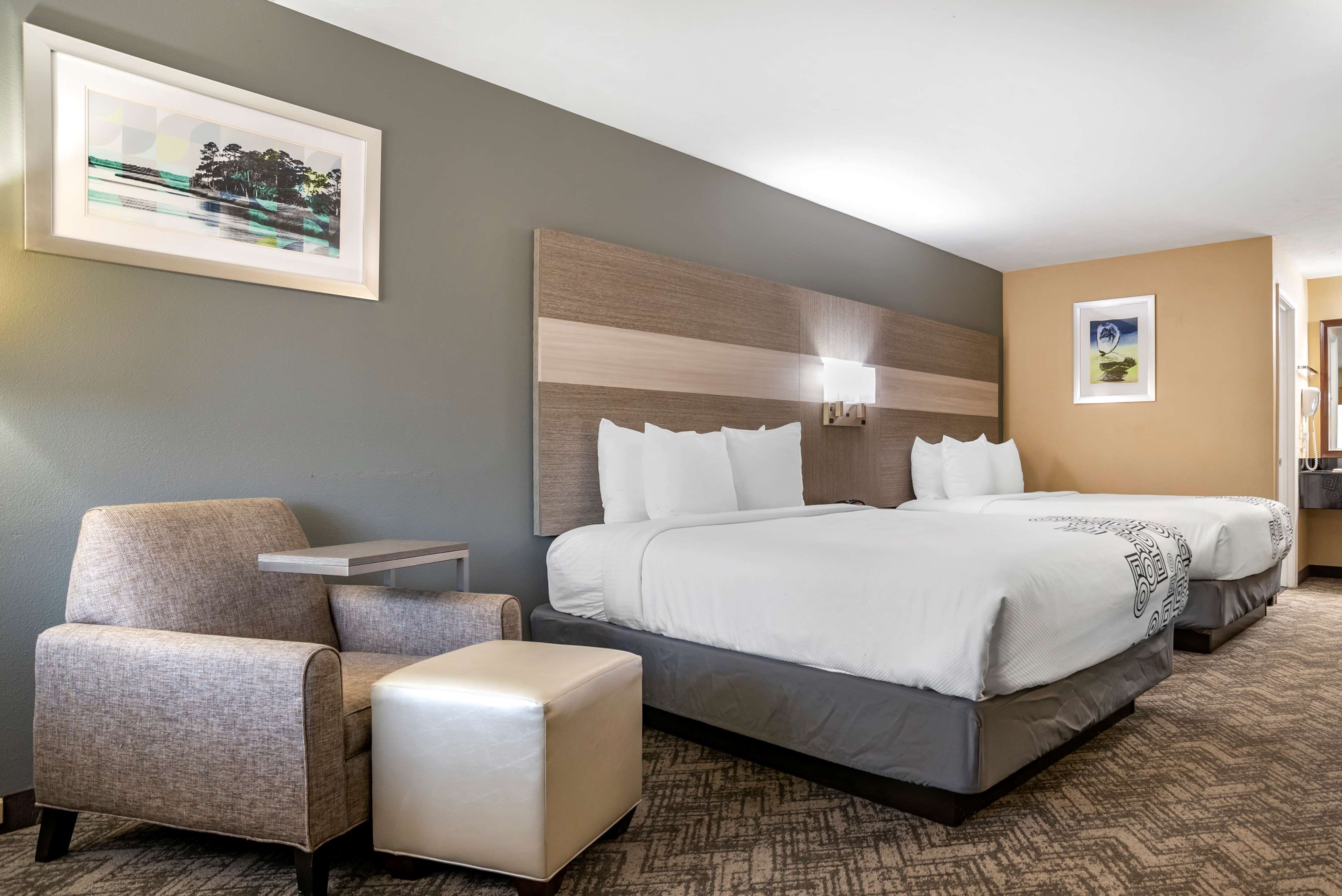 A hotel room with a large bed, a chair, an ottoman, and a nightstand. - Best Western Apalach Inn (Apalachicola)