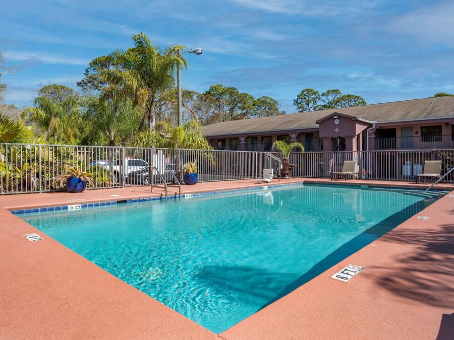 A rectangular pool with clear blue water, surrounded by a metal fence and a red deck.