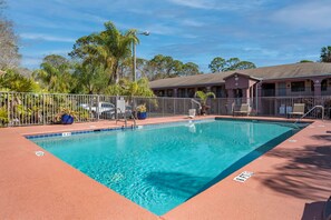 A rectangular pool with clear blue water, surrounded by a metal fence and a red deck. - Best Western Apalach Inn (Apalachicola)