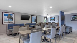 A hotel dining area with tables, chairs, and blue booths.