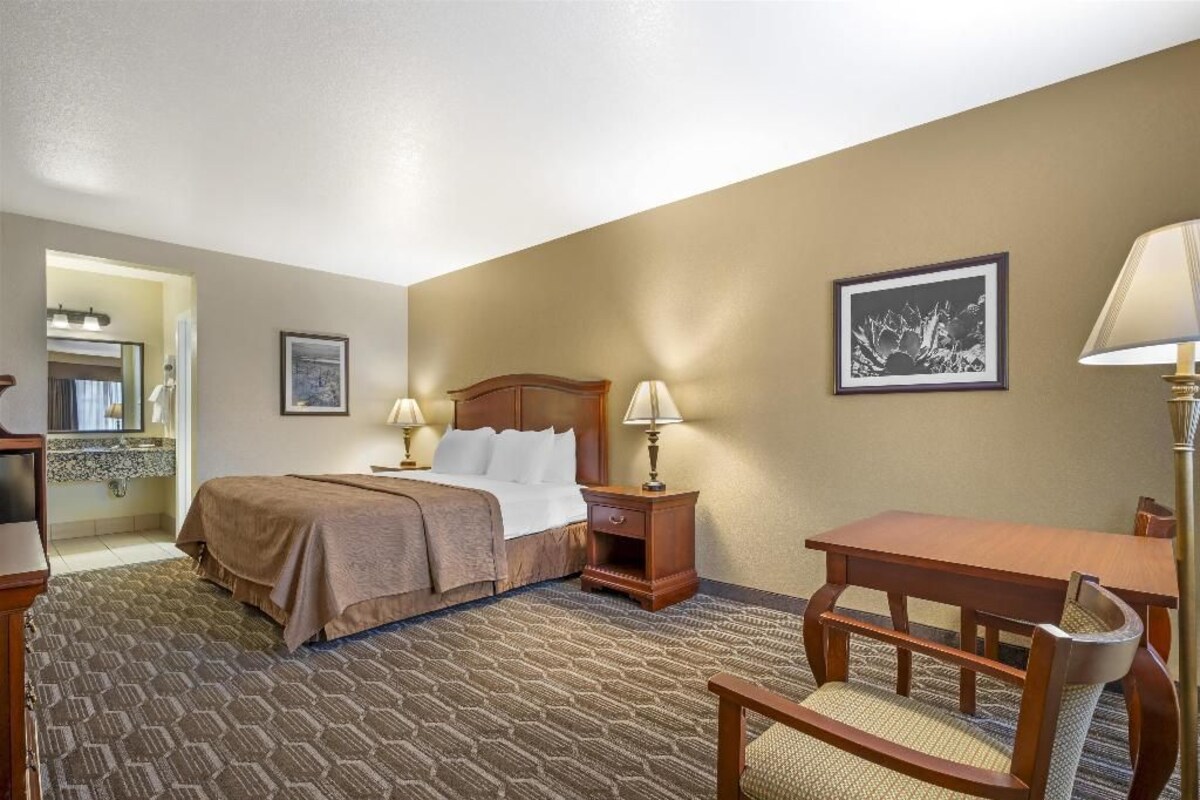 A hotel room with a bed, bedside tables, a desk, and a chair.