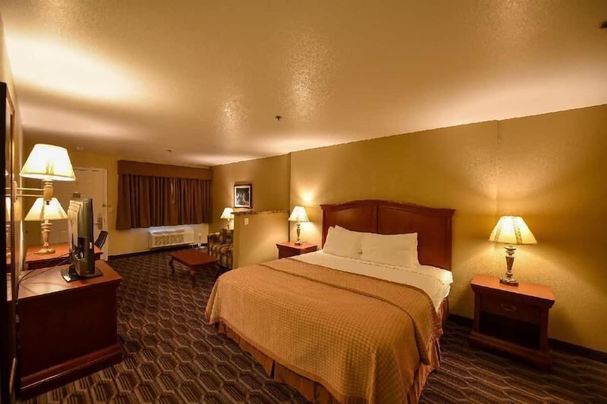 A hotel room with a bed, two bedside tables with lamps, a desk with a telephone, and a chair.