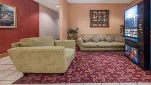 Een woonkamer met een beige bank, een groene fauteuil en een kamerkleed met dessin.