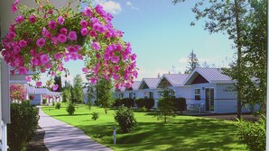 A residential area with a pathway leading to houses with a sloped roof, surrounded by greenery and a clear sky. - Rivers Edge Resort (Fairbanks)