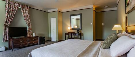 A hotel room with a bed, a TV, a desk, a chair, a lamp, and a ceiling fan.