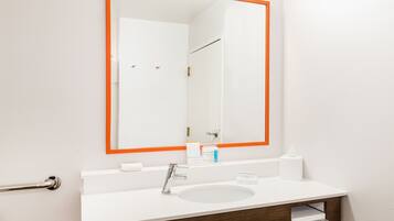 Une salle de bain avec un lavabo blanc, un miroir avec un cadre orange et un porte-serviettes.