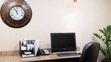 A desk with a Lenovo computer, a telephone, and a magazine rack.