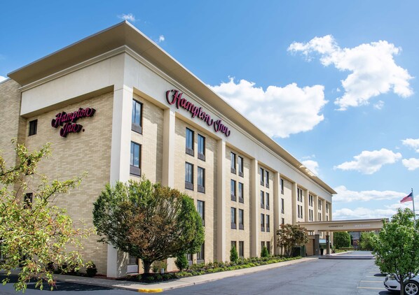 A Hampton Inn hotel with a modern facade, multiple windows, and a clear sky.