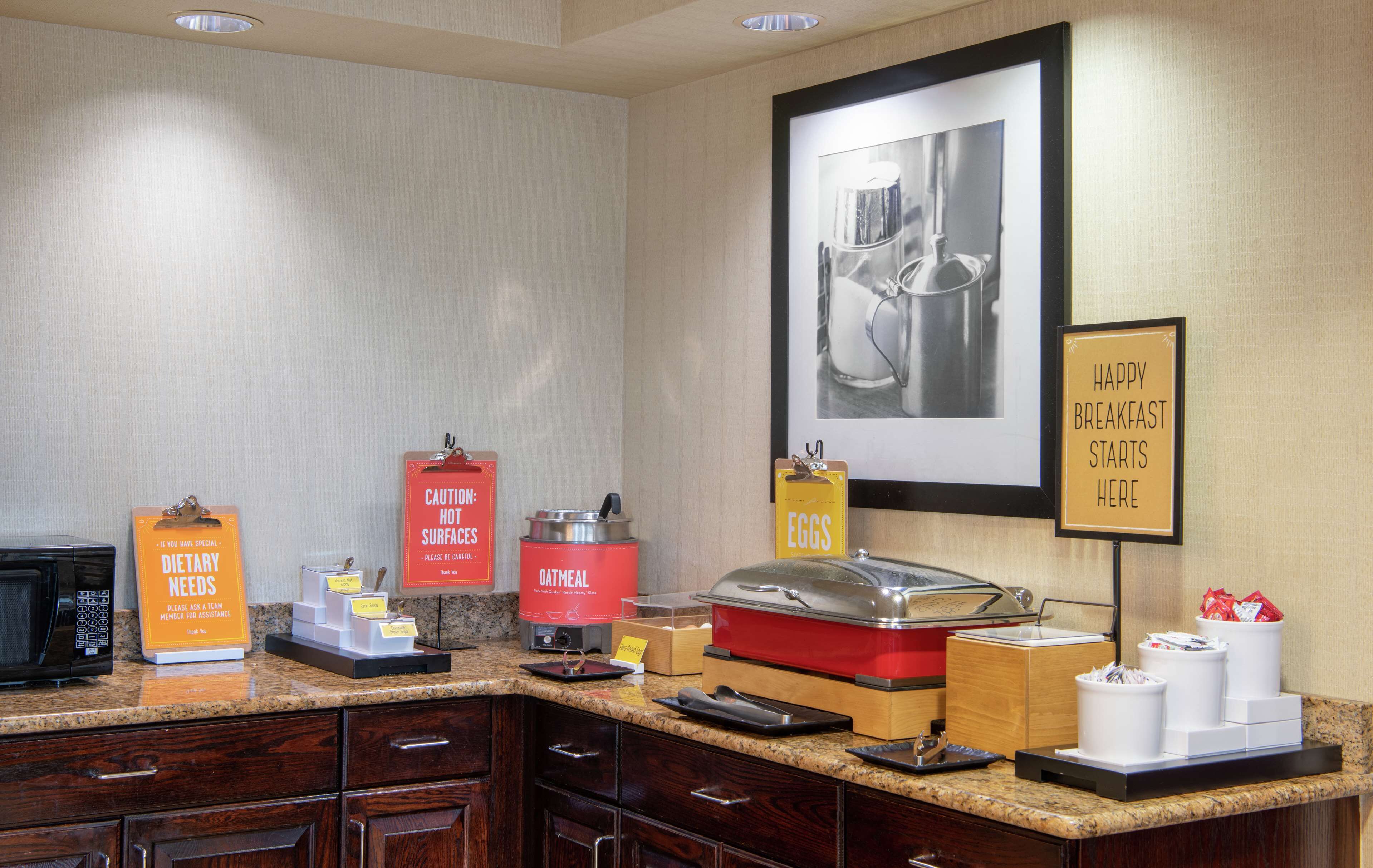 A breakfast bar with dietary needs signage, an oatmeal station, and a sign indicating the breakfast area.