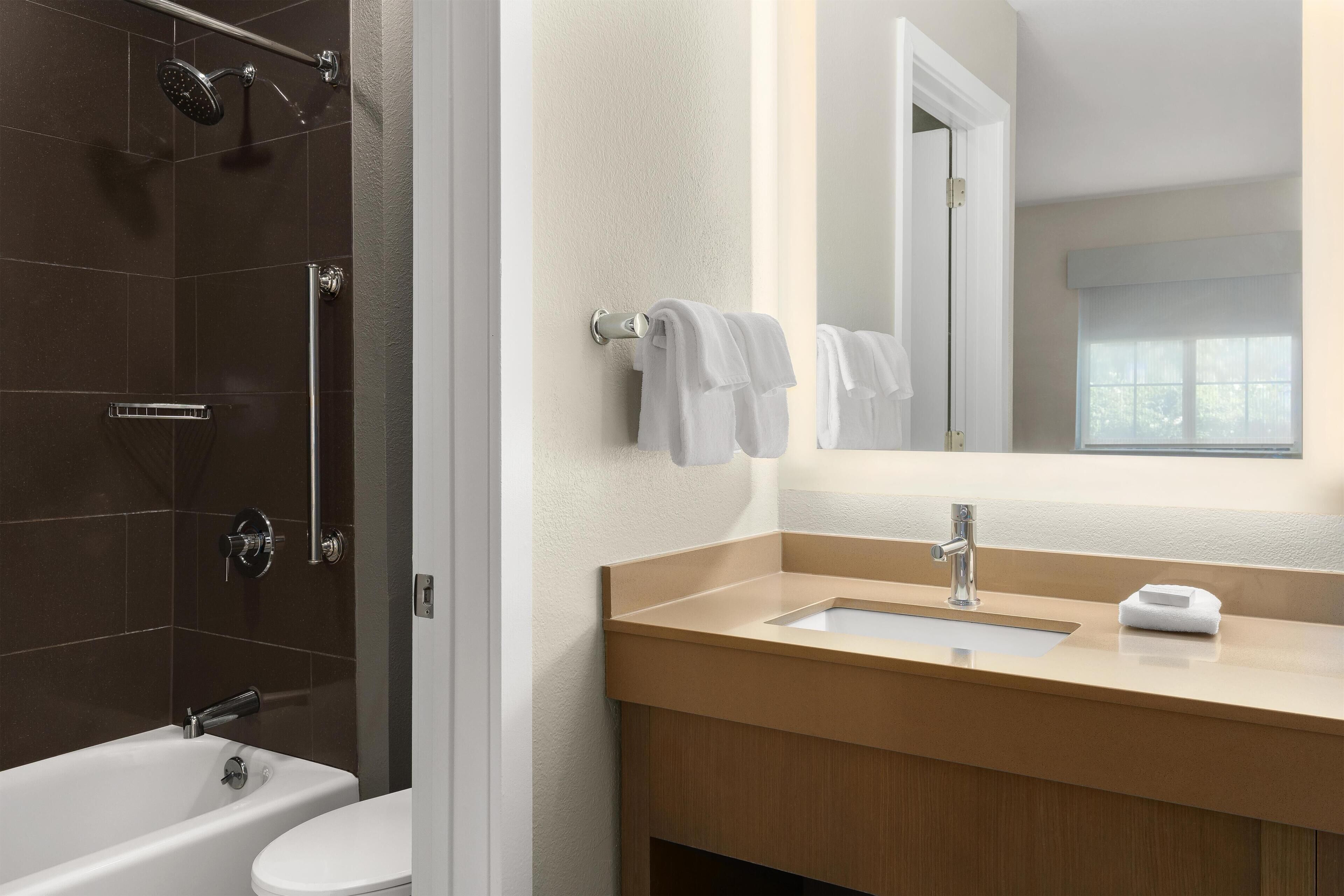 A modern bathroom with a bathtub, toilet, and shower area.
