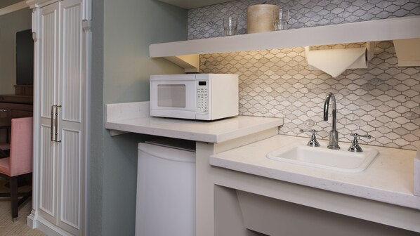 A kitchen with a microwave, sink, and a patterned backsplash.