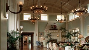 A spacious lobby with multiple chandeliers, elegant furniture, and large windows allowing natural light. - Disney's BoardWalk Villas (Lake Buena Vista)