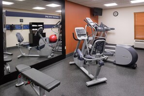A gym with exercise equipment, a bench, and a mirror reflecting the room. - Hampton Inn Elkhart IN (Elkhart)