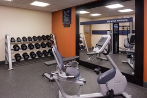 Ein Fitnessraum mit Trainingsgeräten, einem Spiegel und einem motivierenden Spruch.