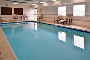 A swimming pool with lounge chairs and a warning sign on the wall.