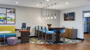 Una hall d'albergo moderna con area bar, posti a sedere e opere d'arte alle pareti.