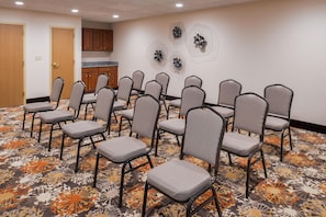 A conference room with rows of chairs, a patterned carpet, wooden cabinets, and wall art. - Hampton Inn Elkhart IN (Elkhart)