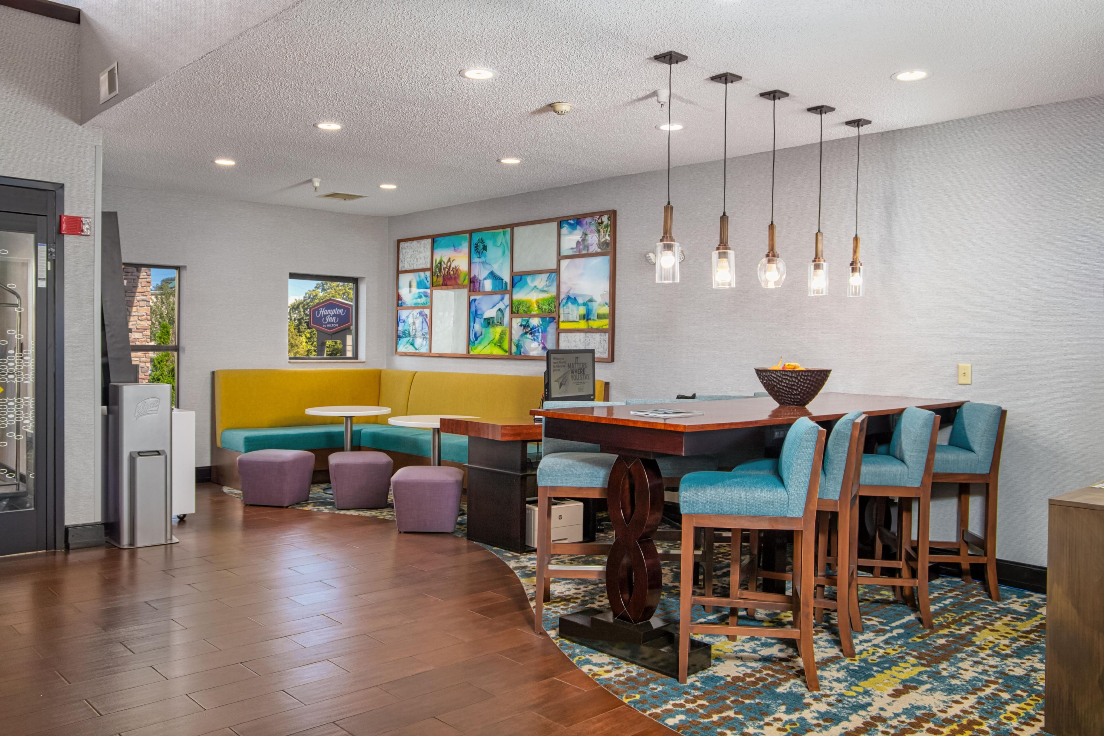 A hotel lobby with a seating area, a reception desk, and artwork on the walls.