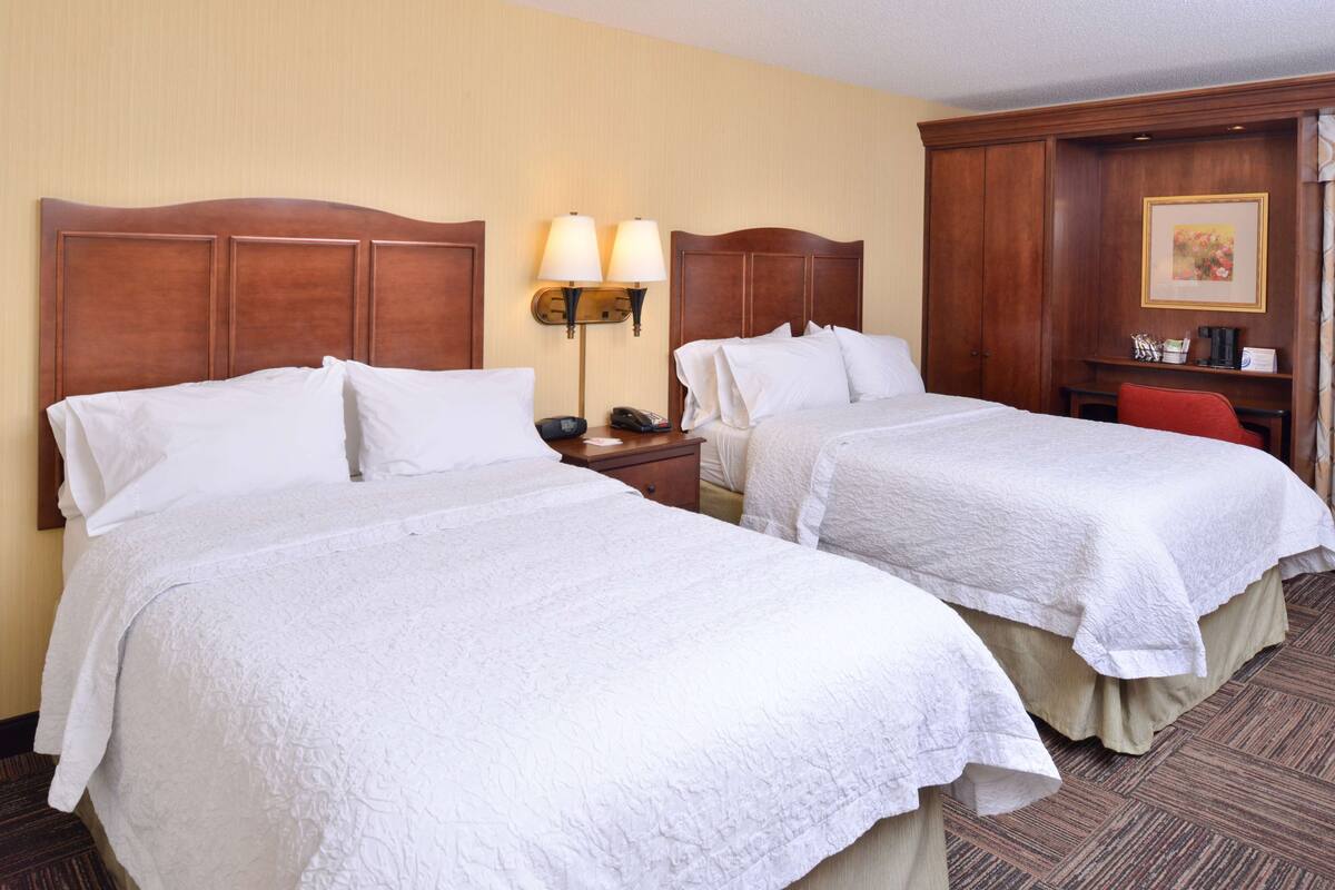 Two single beds with wooden headboards, a nightstand with a lamp, and a small table with a chair.
