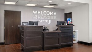 Una reception con un cartello che riporta 'Benvenuti nello Stato dell'Indiana', il logo Hilton e un frigorifero con bevande.
