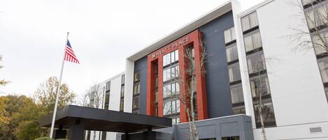 A modern building with a sign reading "HYATT PLACE" and an American flag.