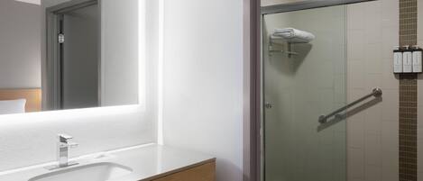 Uma casa de banho moderna com um espelho grande, lavatório e cabine de duche com vidro.