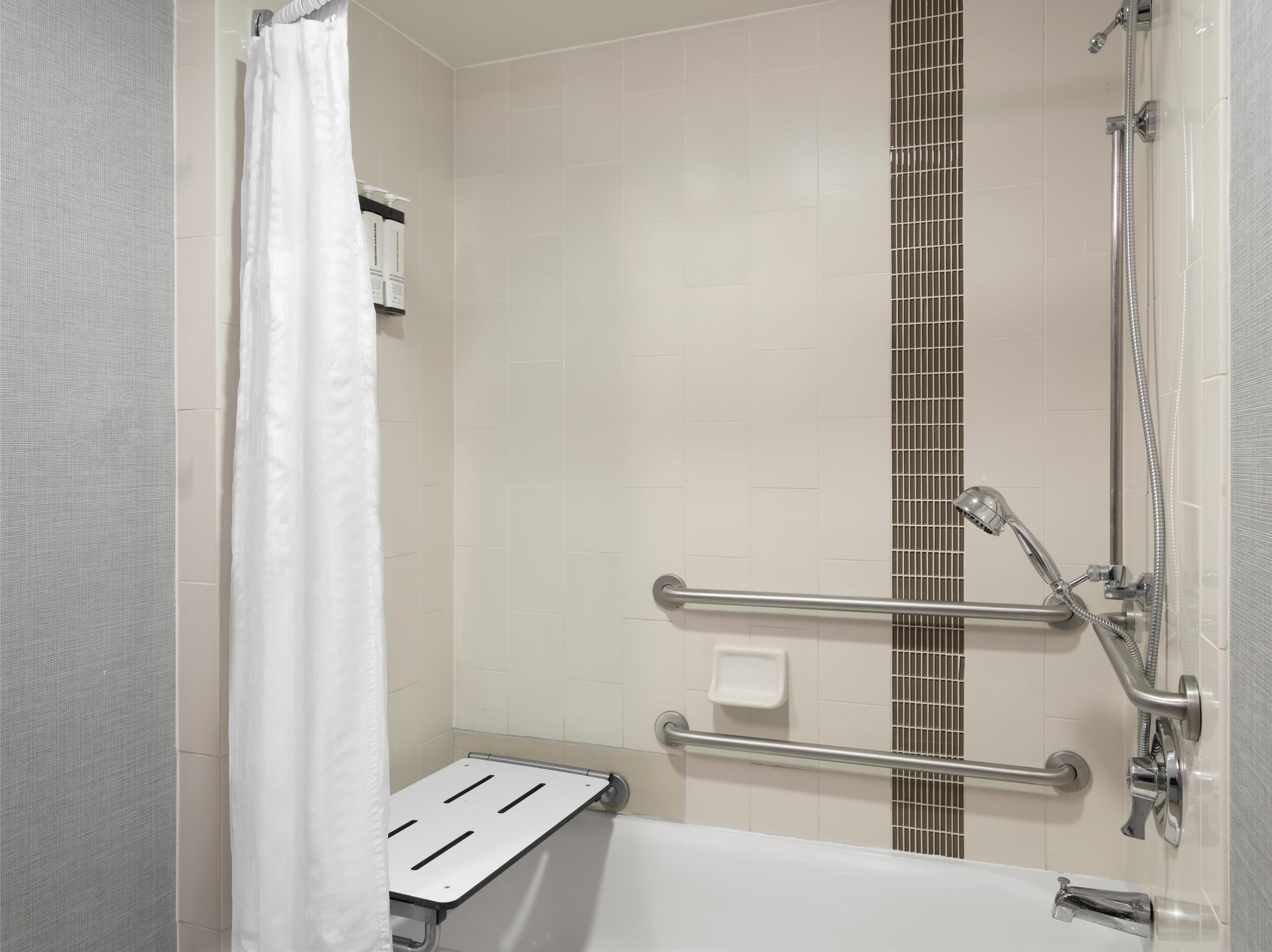 Un espace douche équipé d’une barre d’appui, d’un pommeau de douche à main et d’une baignoire.